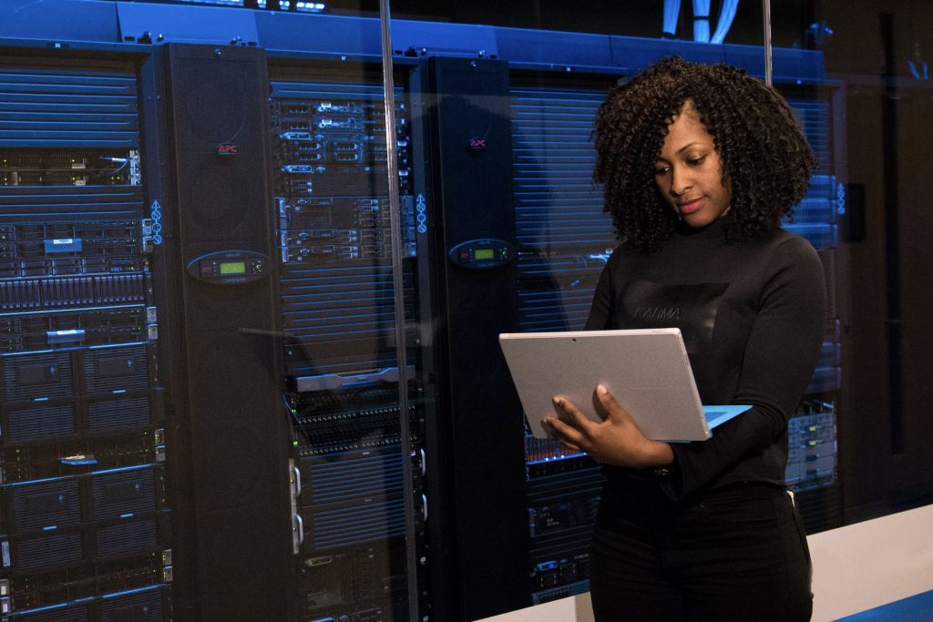 woman holding laptop in front of servers